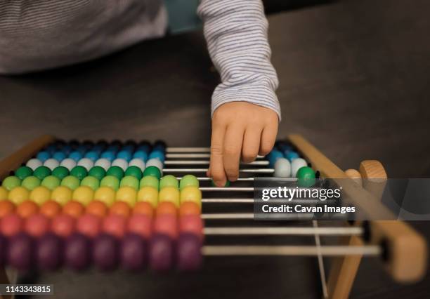 cropped hand of girl using abacus on table at home - beads stock pictures, royalty-free photos & images