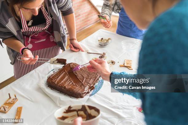 high angle view of family making chocolate cake on table at home - chocolate cake foto e immagini stock