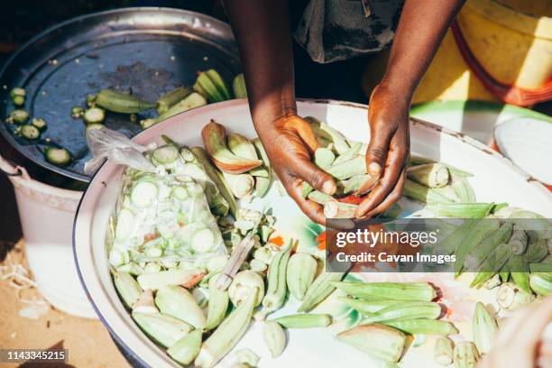 cropped hands of vendor arranging okras in plate at market - okra - fotografias e filmes do acervo