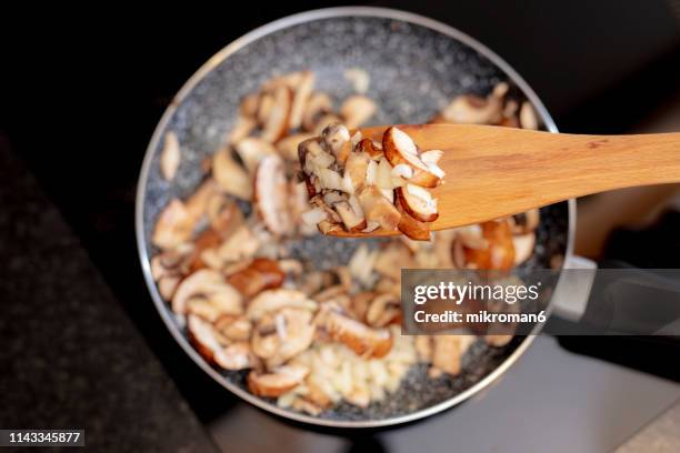 woman stirring sliced brown mushrooms in frying pan - mushroom 個照片及圖片檔