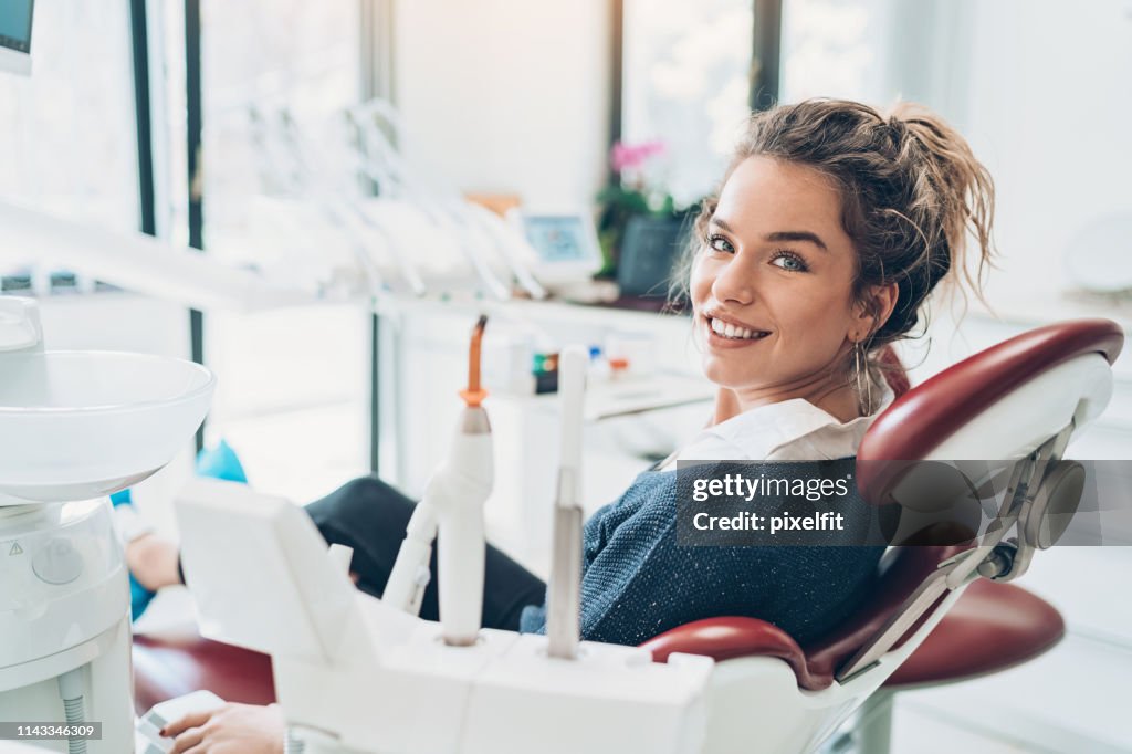 Mulher nova que senta-se na cadeira de um dentista