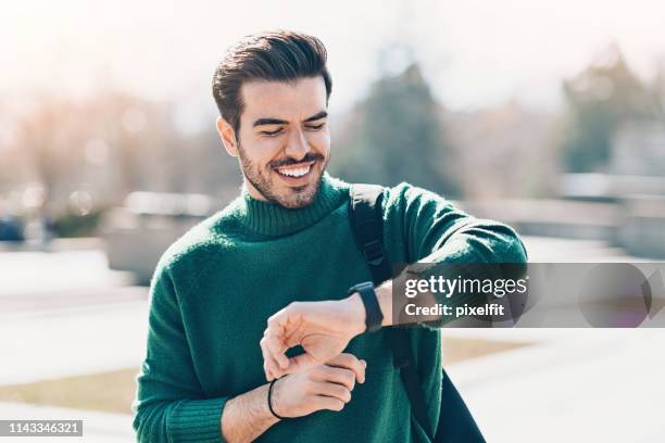 young man checking his smart watch - wristwatch imagens e fotografias de stock