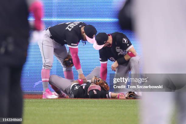 Leury Garcia of the Chicago White Sox is tended to by Yolmer Sanchez and Ryan Cordell after crashing into the electronic scoreboard on the wall after...