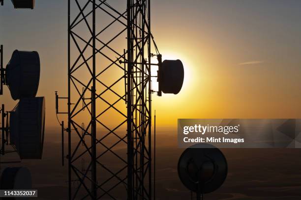 silhouette of communications tower against sunset sky - communications tower sunset stock pictures, royalty-free photos & images