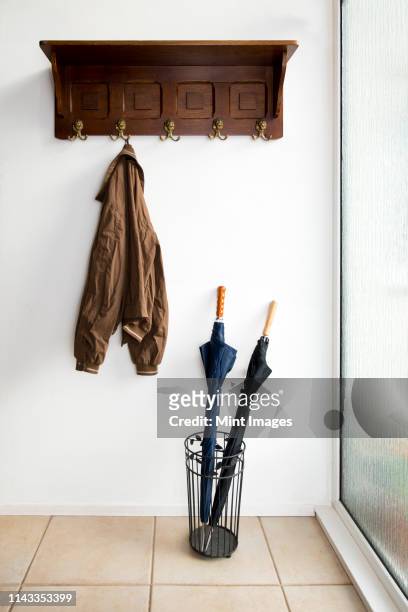 jacket and umbrellas in foyer of home - overcoat stock pictures, royalty-free photos & images