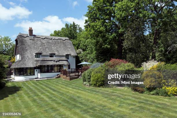 thatched roof cottage - landhaus stock-fotos und bilder