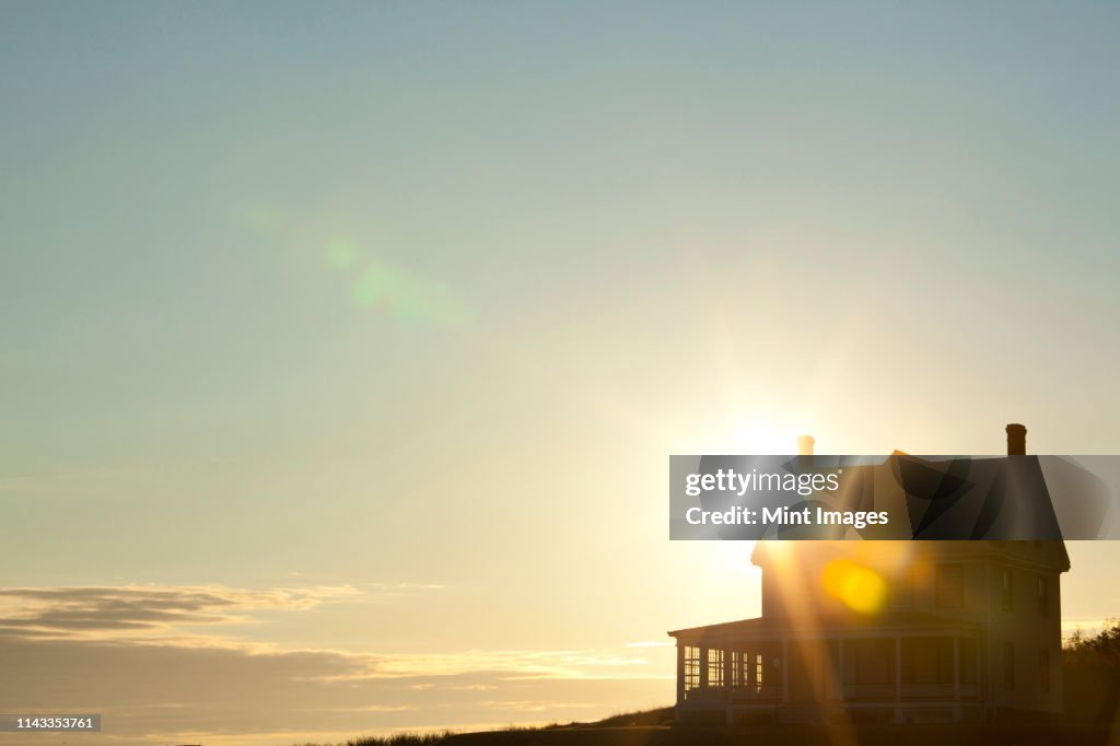 Sun shining behind rural house