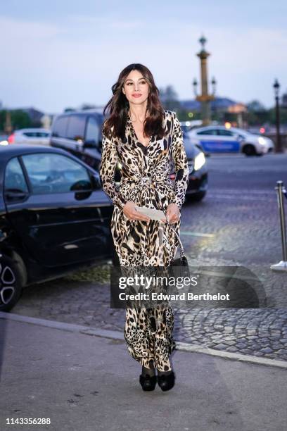 Monica Bellucci wears a low-cut beige and black cheetah print long flowing dress, a black quilted bag, black velvet platform sandals, on April 12,...