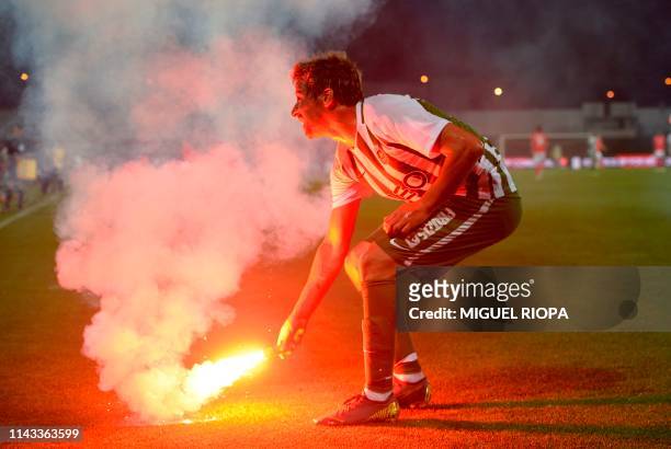 Rio Ave's Portuguese forward Fabio Coentrao holds a flare thrown by Benfica's supporters during the Portuguese league football match Rio Ave FC vs SL...