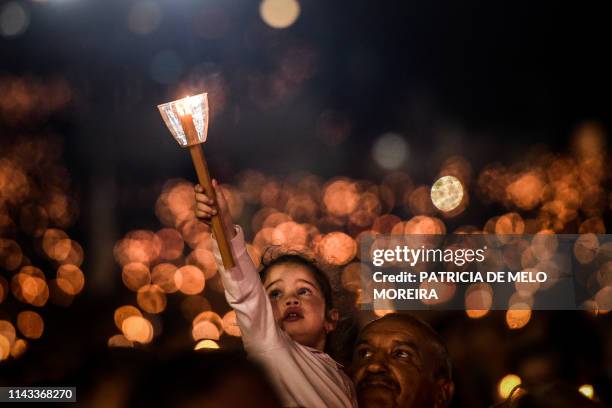 Child holds a candle during the candle procession at the Fatima shrine in Fatima, central Portugal, on May 12, 2019. - Thousands of pilgrims...