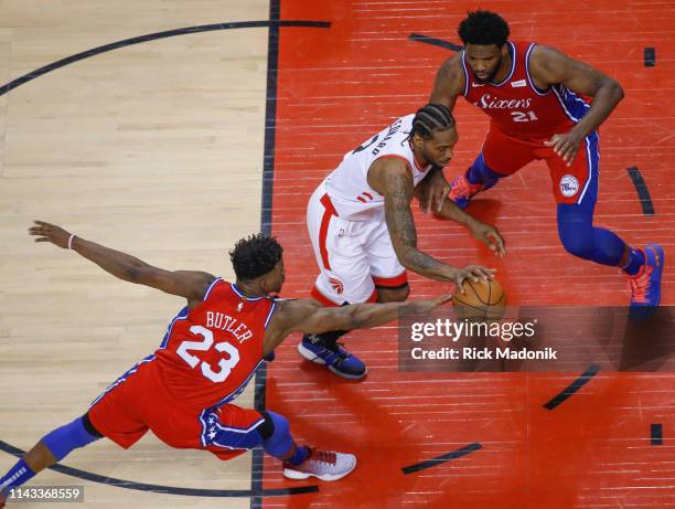 Philadelphia 76ers guard Jimmy Butler gets his hand to the ball as Philadelphia 76ers center Joel Embiid fronts a driving Toronto Raptors forward...