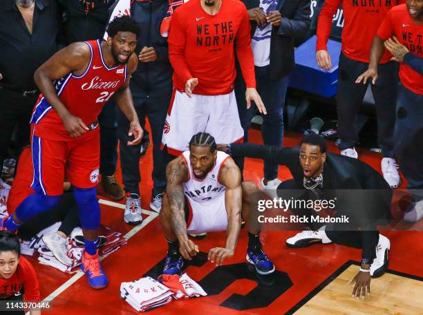 Philadelphia 76ers center Joel Embiid watches from the corner as Toronto Raptors forward Kawhi Leonard squats down and sticks out his tongue waiting...