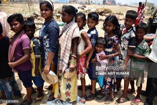 In this photo taken on May 12 Indian children queue to collect food handouts in Puri in the eastern Indian state of Odisha, following Cyclone Fani. -...