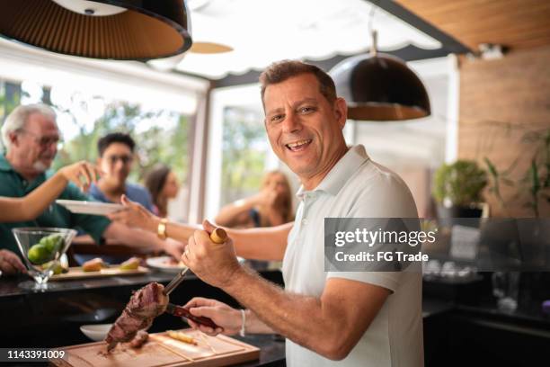 ritratto dell'uomo che taglia carne picanha durante il barbecue - barbecue foto e immagini stock