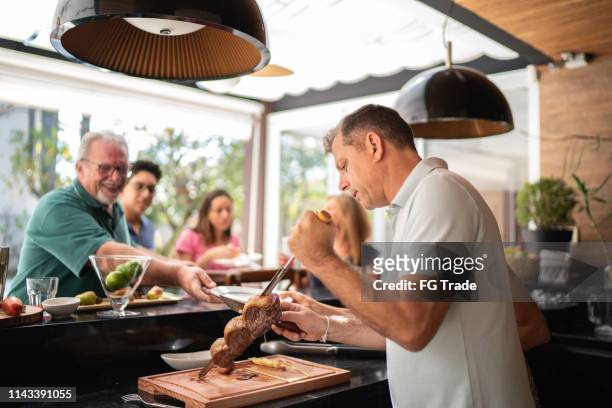 man cutting picanha meat during barbecue - brazilian culture stock pictures, royalty-free photos & images