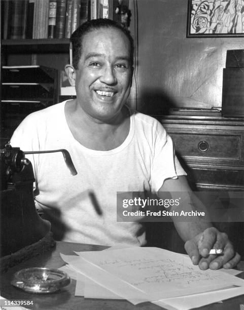 Portrait of American author Langston Hughes as he sits at a desk, 1954.