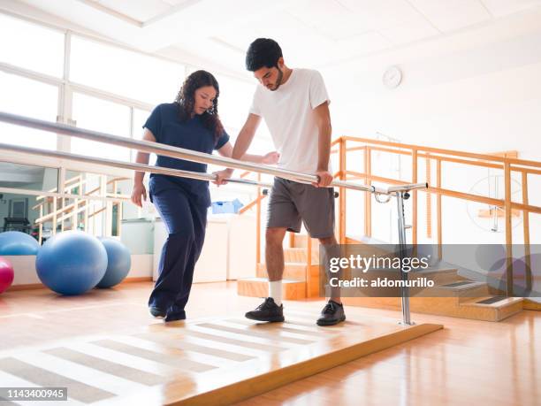 male patient giving small steps in parallel bars - parallel bars stock pictures, royalty-free photos & images