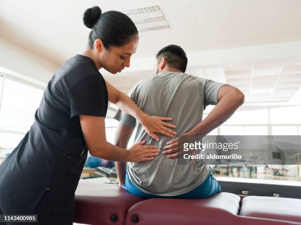 female massage therapist massaging patient's back - back pain man stock pictures, royalty-free photos & images