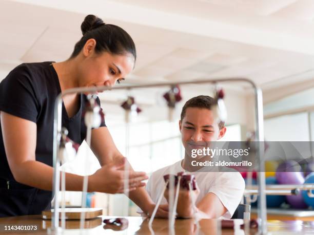 tiener jongen die hand met apparaat uitoefent - ergotherapie stockfoto's en -beelden