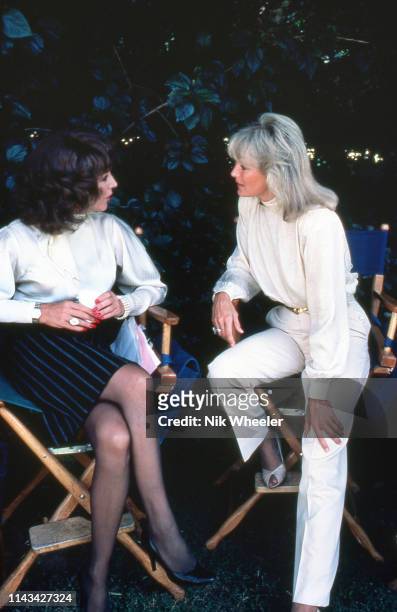 Actresses joan Collins and linda evans chat during break in filming on set of television hit show "Dynasty" in Hollywood circa 1984: