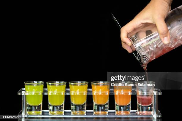 bartender pouring strong alcoholic drink into small glasses on bar - barman tequila stockfoto's en -beelden