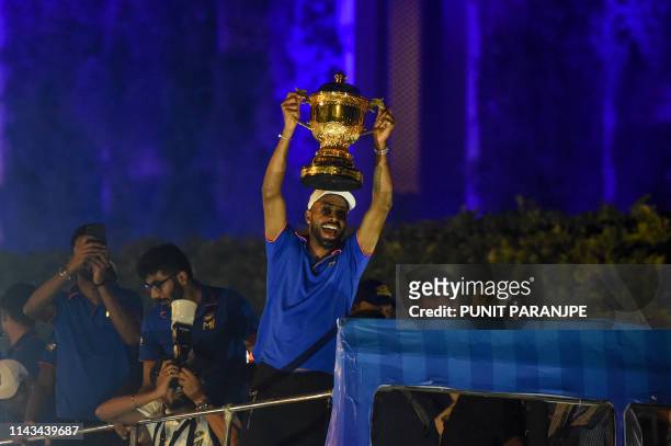 Mumbai Indians cricket player Hardik Pandya holds the winning cup as the team travels in a open bus during a celebration procession after arriving in...