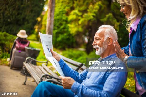 an elderly couple reads newspapers in the park and rests from the trip - the weekend in news around the world stock pictures, royalty-free photos & images