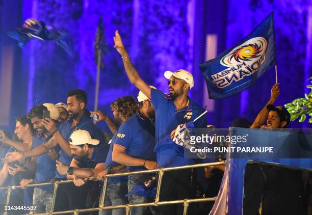 Mumbai Indians cricket player Hardik Pandya throws a team flag as the team members travel in a open bus during a celebration procession after...