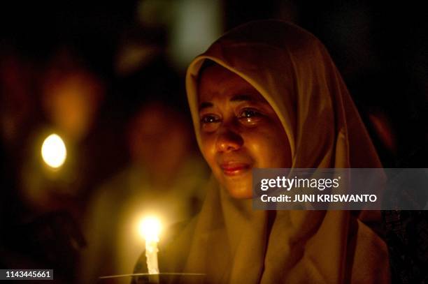 An Indonesian Muslim woman cries during a candlelight vigil to remember the victims of deadly suicide bombings carried out one year ago, outside the...