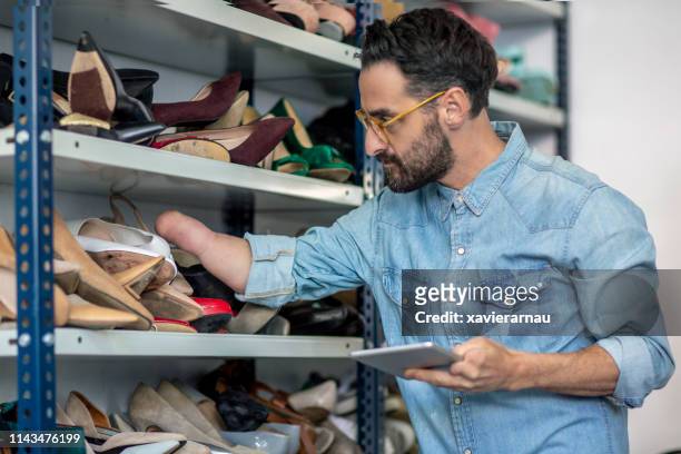 gehandicapte zakenman die schoenen onderzoekt bij studio - shoe collection stockfoto's en -beelden