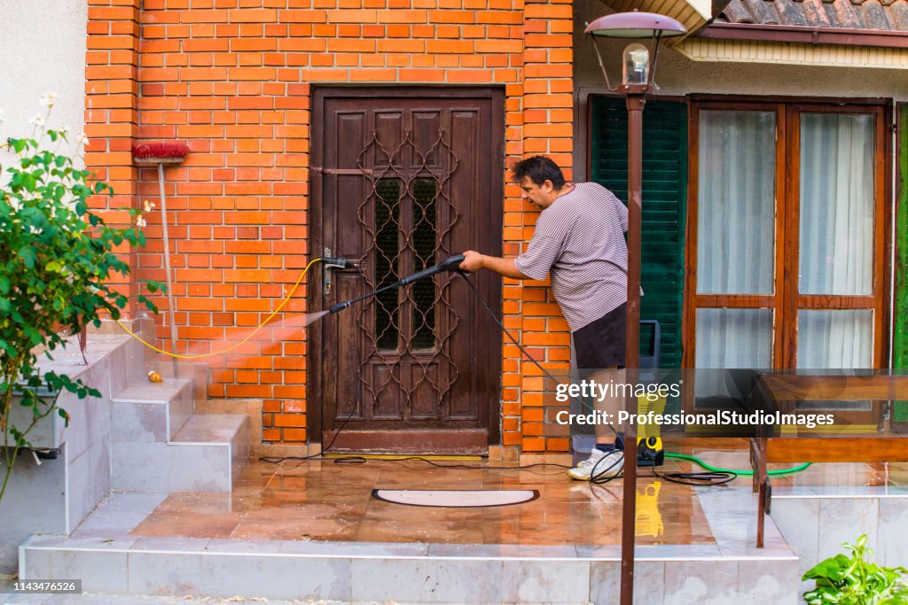 Mann reinigt Haus mit Wasserspray