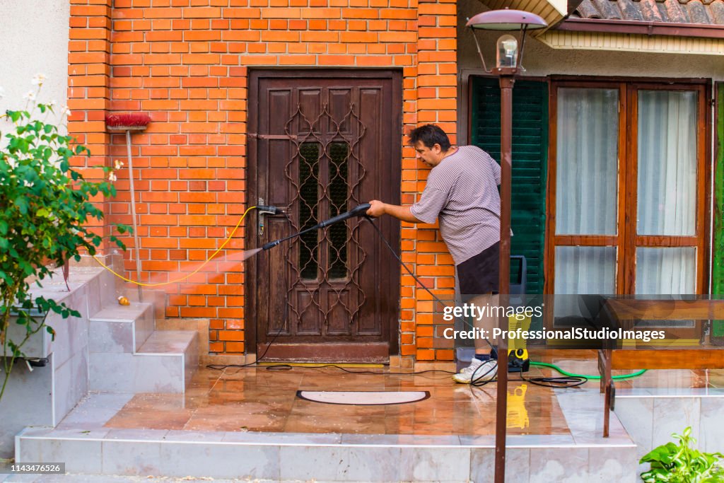 Hombre limpieza de la casa con spray de agua