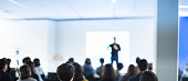 Business Conference Photo. Executive Speaker on Stage. Business Presentation Presenter Speech at Tech Entrepreneur Meeting. Corporate Event Audience. Expert Seminar Lecture Conference Event. Blurred.