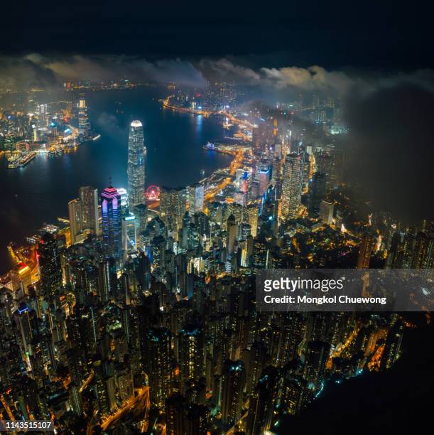 aerial view of hong kong city skyline at night over the clouds - hong kong skyline drone stock pictures, royalty-free photos & images