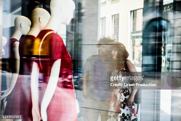 couple in the city looking at clothing store window - etalages kijken stockfoto's en -beelden