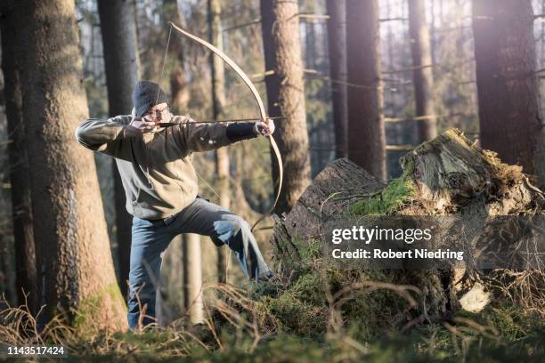 man shooting with bow and arrow in the forest, bavaria, germany - pfeil und bogen stock-fotos und bilder