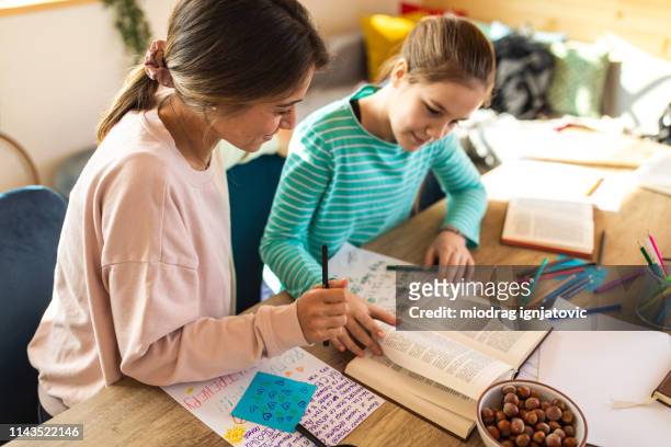 teenage girl studying with help of female teacher - workbook stock pictures, royalty-free photos & images