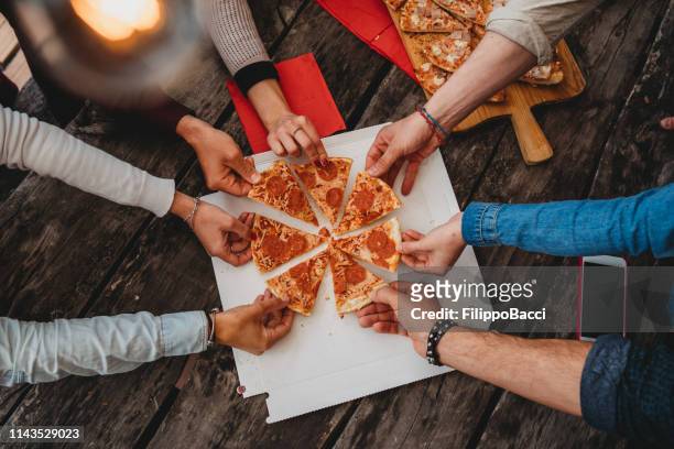 friends taking a slice of pizza from the pizza box - sharing stock pictures, royalty-free photos & images
