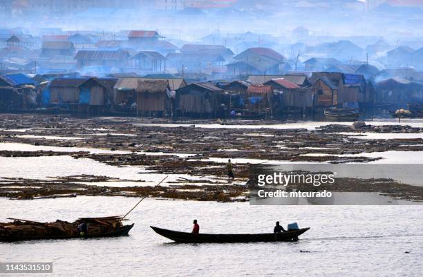 makoko 浮動村----獨木舟、漂浮的原木、濃煙和高架上的房屋, 奈及利亞拉各斯 - lagos skyline 個照片及圖片檔