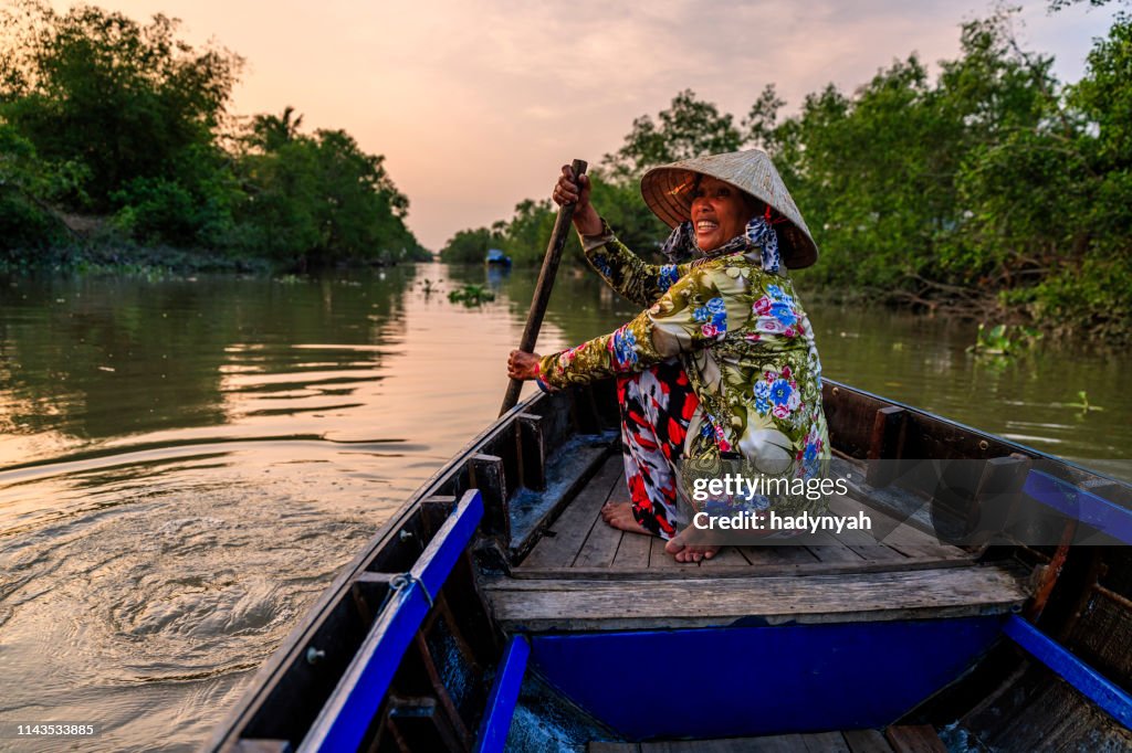 Vietnamese woman rowing a boat, Mekong River Delta, Vietnam