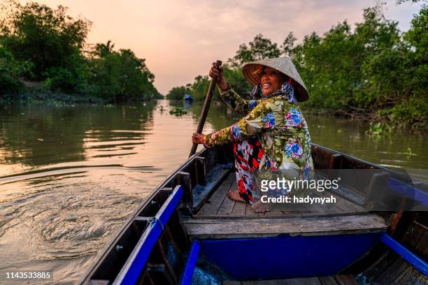 vietnamese woman rowing a boat, mekong river delta, vietnam - vietnam stock pictures, royalty-free photos & images