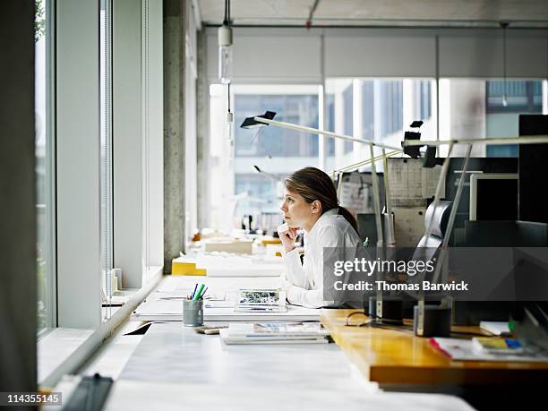 architect sitting at desk looking out window - woman day dreaming stockfoto's en -beelden