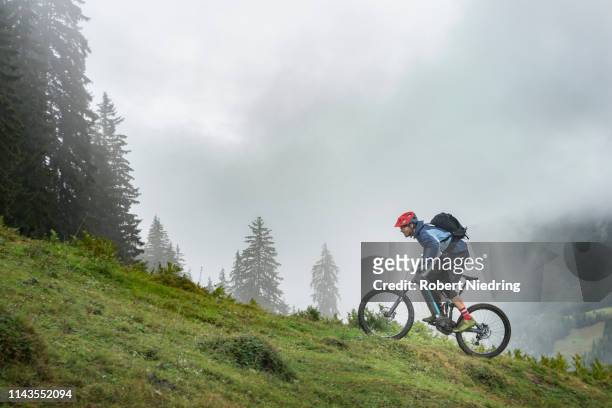man with pedelec riding uphill in mountains, saalfelden, tyrol, austria - colina acima imagens e fotografias de stock