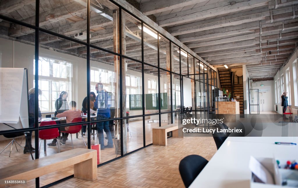 A team is working behind glass in a large modern office space