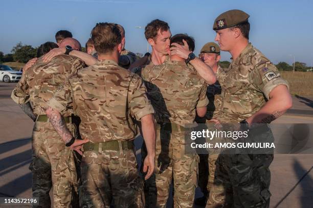 British soldiers console each other after carrying on the plane the coffin, covered with a Britain's flag, of the remains of their colleague Mathew...