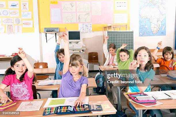 group of pupils raising their fingers in classroom - 立てた指 ストックフォトと画像