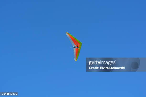 hang glider over the pacific ocean against blue sky - drachenfliegen stock-fotos und bilder