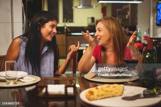 mother and daughter eating pizza together at dining table and talking. - teenagers eating with mum stock pictures, royalty-free photos & images