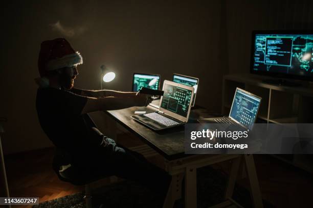 man hacking and committing internet crime by using laptops - christmas thief stock pictures, royalty-free photos & images