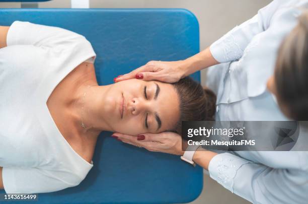 gpr - global postural re-education, doctor holding patient's head - osteopath stock pictures, royalty-free photos & images